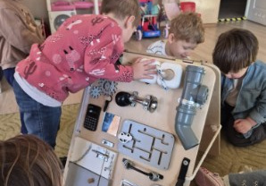 Dzieci bawią się tablicami manualno-sensorycznymi