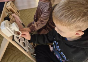 Dzieci bawią się tablicami manualno-sensorycznymi