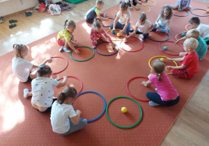 Dzieci biorą udział w ćwiczeniach gimnastycznych z obręczami i piłkami