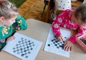 Dzieci kolorują szachownicę w ramach zajęć szachowych