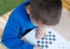 Chłopiec koloruje szachownicę w ramach zajęć szachowych