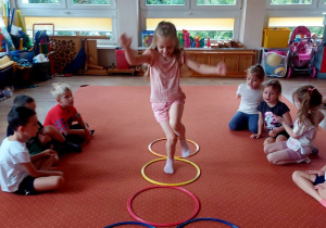 Dzieci biorą udział w ćwiczeniach gimnastycznych z obręczami