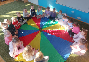 Dzieci siedzą w kole na chuście animacyjnej