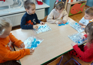 Dzieci malują paluszkami farbą umieszczoną w folii