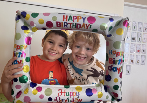 Chyłopcy pozują do zdjęcia trzymając ramkę urodzinową